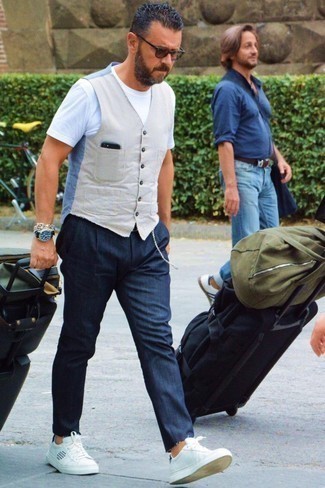 Navy Jeans with White Leather Low Top Sneakers Summer Outfits For Men: We love the way this pairing of a beige waistcoat and navy jeans instantly makes a man look polished and smart. A trendy pair of white leather low top sneakers is an effortless way to add a touch of stylish casualness to your ensemble. We can't get enough of this getup for extremely hot afternoons.
