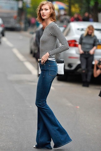 Karlie Kloss wearing White Leather Belt, White and Black Leather Clutch, Navy Flare Jeans, White and Black Horizontal Striped Long Sleeve T-shirt