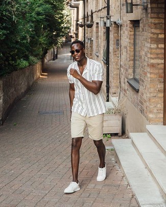 Tan Shorts Outfits For Men: To achieve a laid-back getup with a twist, you can easily wear a white and black vertical striped short sleeve shirt and tan shorts. Add a pair of white canvas low top sneakers to the mix et voila, your look is complete.