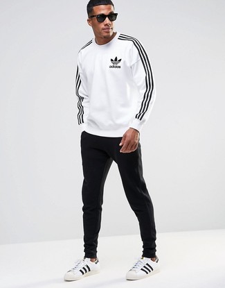 White Print Sweatshirt Outfits For Men: If you're looking for an edgy and at the same time dapper getup, choose a white print sweatshirt and black sweatpants. Kick up your whole look with a pair of white and black leather low top sneakers.
