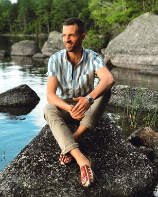 Olive Jeans Outfits For Men: Beyond dapper and comfortable, this combination of a white and blue vertical striped short sleeve shirt and olive jeans will provide you with variety. Add a pair of multi colored print canvas slip-on sneakers to the mix and ta-da: the getup is complete.