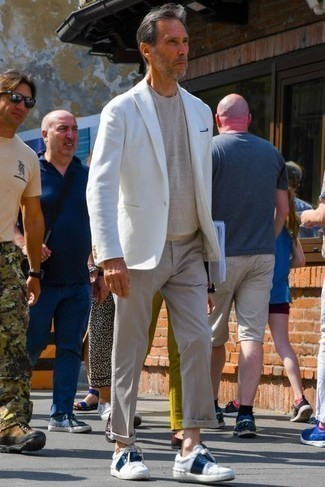White Blazer Outfits For Men: Show that you do semi-casual men's style like a pro in a white blazer and grey chinos. White and navy leather low top sneakers will bring an easy-going vibe to this look.