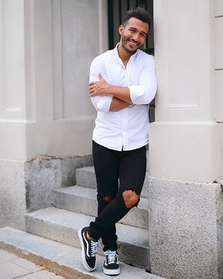 Black Low Top Sneakers with White and Black Long Sleeve Shirt Outfits For Men: This pairing of a white and black long sleeve shirt and black ripped skinny jeans sends off a so-chill and approachable kind of vibe. Black low top sneakers will breathe an added dose of style into an otherwise mostly dressed-down outfit.
