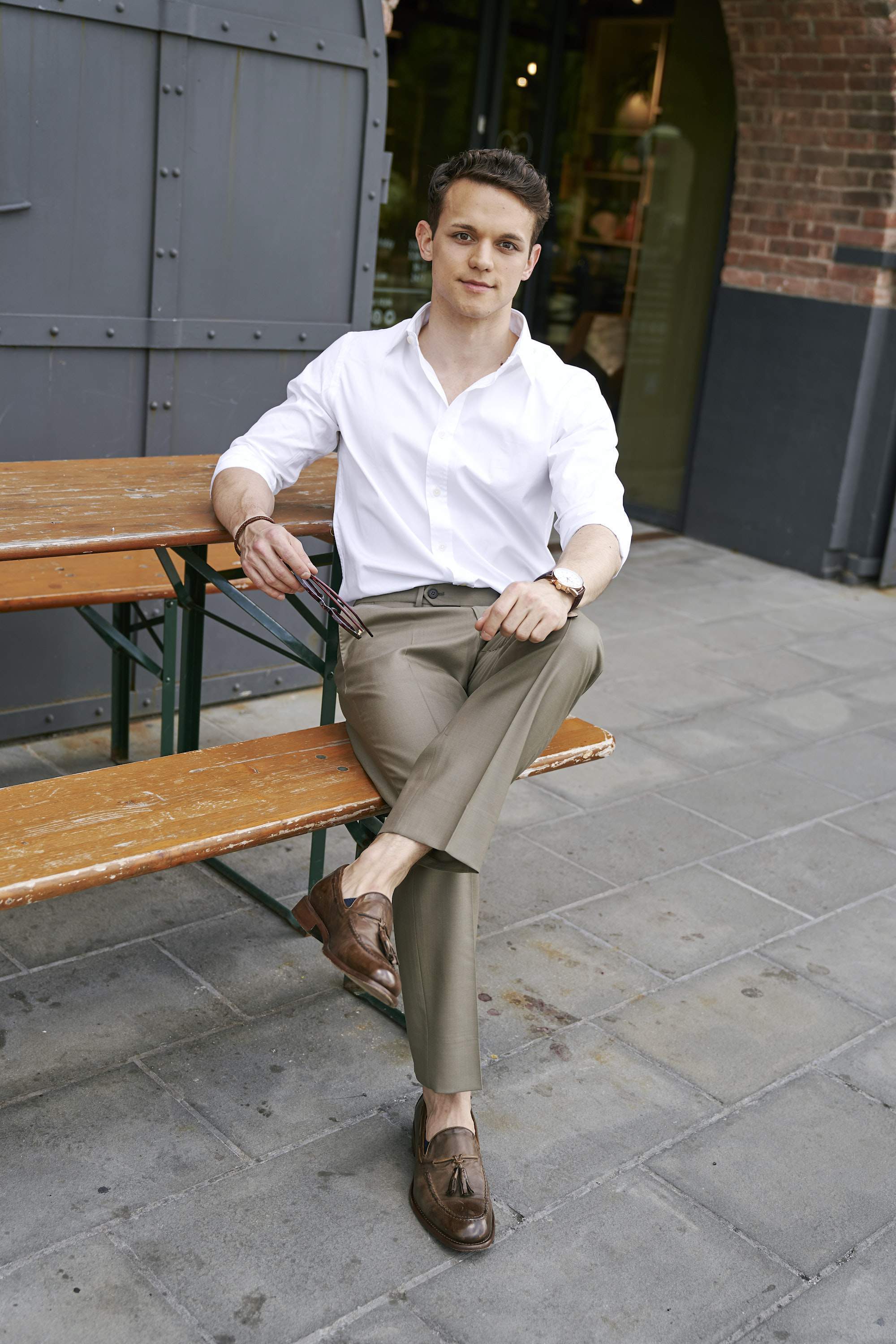 a young man wearing a white shirt and brown pants Stock Photo by Icons8
