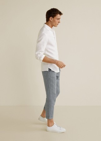 White Long Sleeve Shirt Outfits For Men: Nail the casually dapper ensemble in a white long sleeve shirt and grey vertical striped chinos. Throw in white leather low top sneakers and ta-da: the outfit is complete.