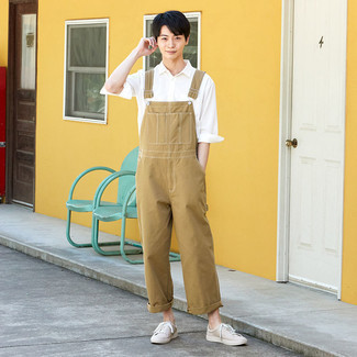 Beige Overalls Outfits For Men: If it's ease and functionality that you love in menswear, go for a white long sleeve shirt and beige overalls. Our favorite of an endless number of ways to complement this ensemble is with a pair of beige canvas low top sneakers.