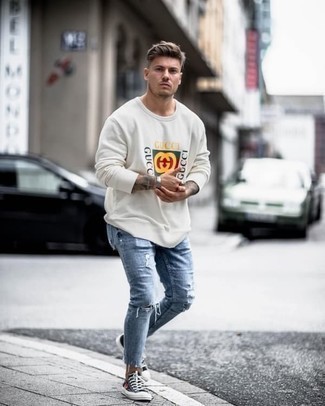 White Print Sweatshirt Outfits For Men: If you're obsessed with relaxed dressing when it comes to fashion, you'll love this contemporary combination of a white print sweatshirt and light blue ripped jeans. Black print canvas low top sneakers are an effortless way to upgrade your ensemble.