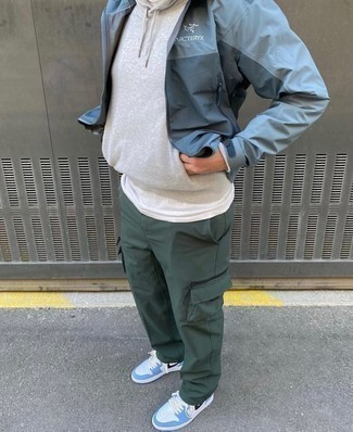 Blue Windbreaker Outfits For Men: A blue windbreaker and dark green cargo pants paired together are a smart match. For extra style points, add a pair of light blue leather low top sneakers to the mix.