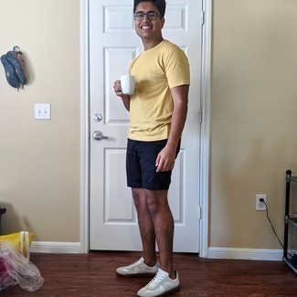 Yellow Crew-neck T-shirt Outfits For Men: Go for a simple yet cool and relaxed option combining a yellow crew-neck t-shirt and navy shorts. On the shoe front, this look pairs brilliantly with white leather low top sneakers.