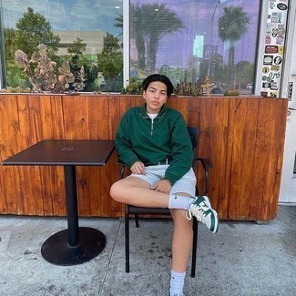 Dark Green Zip Neck Sweater Outfits For Men: This combination of a dark green zip neck sweater and grey sports shorts speaks casual cool and relaxed menswear style. A pair of white and green leather low top sneakers is a great choice to complement your getup.